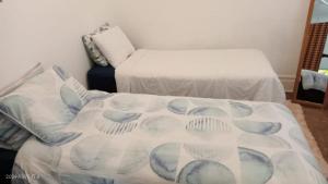 a room with two beds and a couch with a blanket at Palm Terrace Guesthouse in Durban