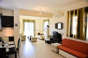 a living room with a red couch and a tv at Villa Eli Keratokampos in Kastrí