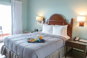 a hotel room with a bed with a tray of food on it at Trade Winds Hotel Antigua in Dickenson Bay