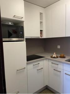 a kitchen with white cabinets and a microwave at Hotel Europe App 303 in Davos