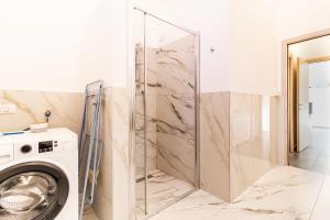 a glass shower door in a bathroom with a washing machine at Malpensa sweet home in Busto Arsizio