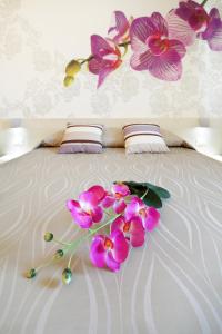 un bouquet de fleurs roses sur un lit dans l'établissement Hotel Alex, à Lignano Sabbiadoro