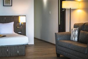 a bedroom with a bed and a chair and a lamp at Trade Winds Hotel Antigua in Dickenson Bay
