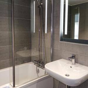 a bathroom with a sink and a shower and a tub at Trade Winds Hotel Antigua in Dickenson Bay