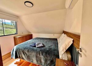 a small bedroom with a bed and a window at Chalé da Árvore in Urubici