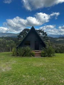 a small black house with a grassy yard at Chalé da Árvore in Urubici
