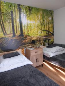 a bedroom with two beds and a mural of a forest at LoftLove roztocze domek in Jędrzejówka