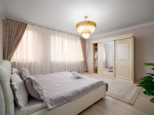 a bedroom with a white bed and a chandelier at Smart Lux 320 in Almaty