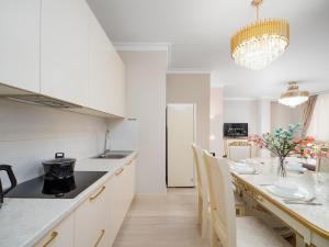 a kitchen with white cabinets and a table with chairs at Smart Lux 320 in Almaty