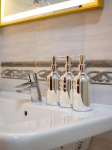 a bathroom sink with three glass bottles on it at Smart Lux 320 in Almaty +38 photos
