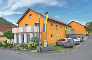 Ramsthal的住宿－Gästehaus Ingrid，一座黄色的房子,前面有一辆汽车