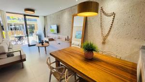 a dining room with a wooden table and a living room at Sunset Villas Milagres - Casa Anahi in Passo de Camarajibe
