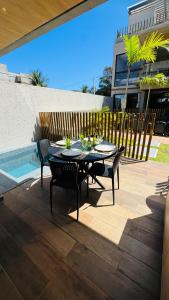 a patio with a table and chairs and a pool at Sunset Villas Milagres - Casa Anahi in Passo de Camarajibe