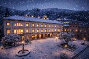 a large building with a courtyard in the snow at night at Mokni's Palais Hotel & SPA in Bad Wildbad