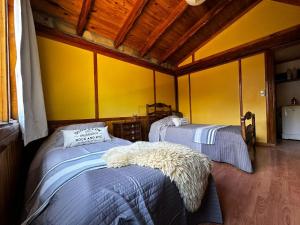 two beds in a room with yellow walls at Sentidos cardinales casa B Encanto in Perito Moreno