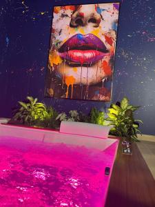 a painting of a lips on a wall with pink lights at Love Room avec Jacuzzi Privatif Loft Sensation Romantique in Renwez