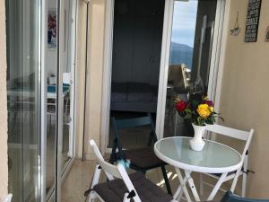 a table and chairs on a balcony with a table and flowers at Apartment bay, Bougainville Bay Resort in Sarandë