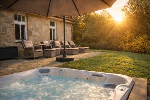 a hot tub in a yard with an umbrella at Villa Emausy in Luhačovice