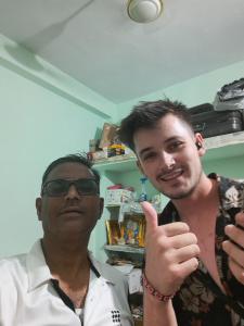 a man giving a thumbs up next to another man at Narmada Gest House in Indore