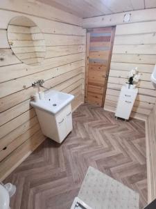 a bathroom with a white sink and a wooden wall at Domek drewniany Szafran in Witów +38 photos