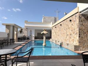 a swimming pool with tables and chairs and an umbrella at Hotel Los Diamantes in Rancho Los Limones