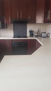 a kitchen with brown cabinets and a black stove at Feel Good in Gqeberha