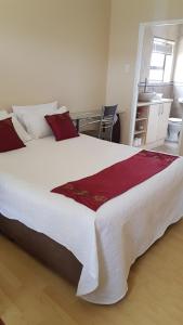 a bedroom with a large white bed with red pillows at Feel Good in Gqeberha