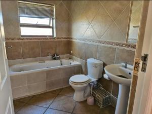 a bathroom with a toilet and a tub and a sink at Feel Good in Gqeberha