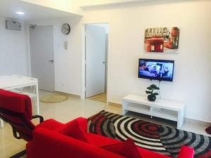 a living room with a red couch and a tv at Sarah Suite@D'Perdana Condo in Kota Bharu