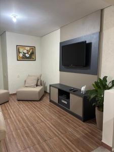 a living room with a flat screen tv and a couch at Casa no Roteiro do Vinho in São Roque