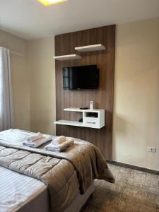 a bedroom with a bed with a tv on the wall at Casa no Roteiro do Vinho in São Roque