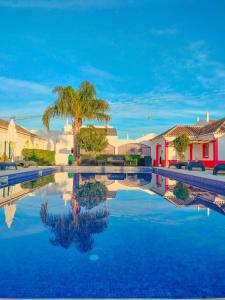 a swimming pool with a palm tree and houses at Maria's Village in Tavira