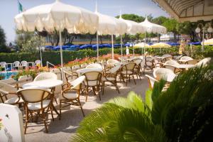 een groep tafels en stoelen met parasols bij Hotel Alexander in Caorle