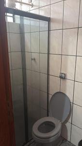 a bathroom with a toilet and a glass door at Hotel Ravena Araraquara in Araraquara