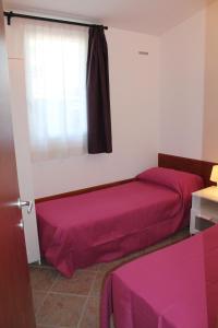 カヴァッリーノ・トレポルティにあるBungalow Gambaroのベッド2台、紫のシーツが備わる窓が付いた客室です。