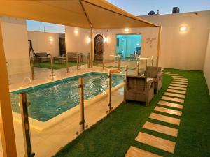 a swimming pool in a house with a green lawn at شاليه لارا in Rayyis