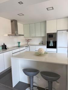a kitchen with white cabinets and a counter with two stools at SeaHorse House in Esposende
