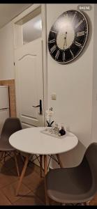 a white table with chairs and a clock on the wall at Roza in Ruma +1 photo