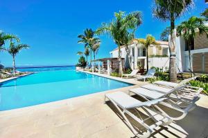 a swimming pool in a house with chairs and palm trees at Paradise luxury White Beach in Paea