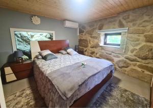 a bedroom with a large bed in a stone wall at O Palheiro in Caramulo