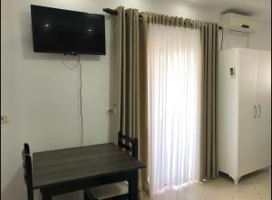 a room with a table and a television on a wall at Poseidon Family Hotel Ksamil in Ksamil