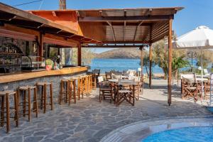a bar with tables and chairs next to a pool at Lena Apartments in Elounda