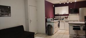 a kitchen with white appliances and purple walls at T2 Voltaire in Bègles