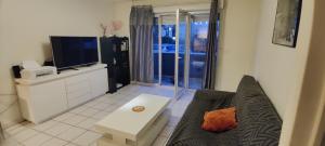 a living room with a couch and a tv at T2 Voltaire in Bègles