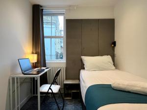 a bedroom with a bed and a laptop on a desk at Park Inn Palace in Dover