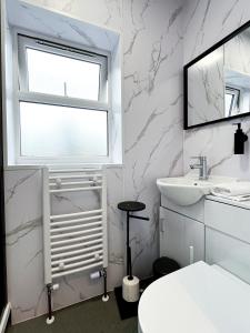 a white bathroom with a window and a sink at Park Inn Palace in Dover +21 photos