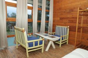 a porch with two chairs and a table and a bed at Hotel YAN Residency Bhimtal - Nainital in Bhīm Tāl
