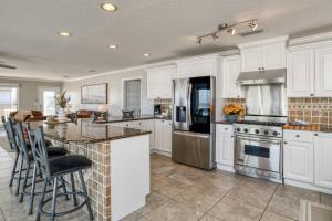 a kitchen with white cabinets and an island with bar stools at High Tide Paradise in St. Augustine
