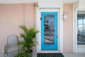 a blue door on a pink house with a plant at High Tide Paradise in St. Augustine +42 photos