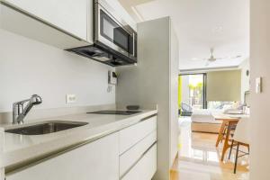 a white kitchen with a sink and a microwave at Central Studio - Rooftop Pool Gym Near Beach in Playa del Carmen